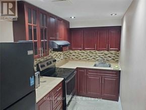 Mississauga (Meadowvale Village) apartment for rent - A kitchen with dark wood cabinets and a black refrigerator.