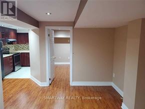 Mississauga (Meadowvale Village) apartment for rent - A real estate listing photo of a room with wood floors and a kitchen area.