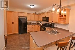 Parry Sound condo for rent - A kitchen with wooden cabinets and a black fridge.