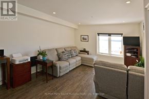 Parry Sound condo for rent - A living room with a grey couch, a wooden table, and a television.