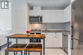 Toronto (Kensington-Chinatown) condo for rent - A modern kitchen with a wooden table and stainless steel appliances.