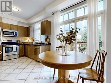 Richmond Hill (Jefferson) townhouse for rent - A kitchen with a table and chairs in the foreground and a balcony with a table and chairs in the background.