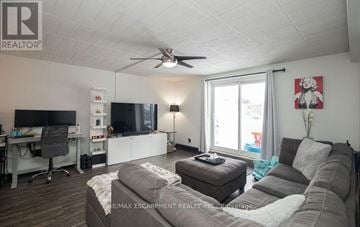 Kitchener condo for rent - A living room with a grey couch and a white ceiling fan.