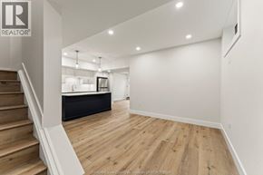 Amherstburg apartment for rent - A spacious room with wooden flooring and a staircase on the left side.
