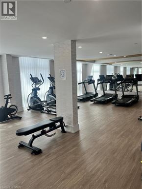 Waterdown condo for rent - A gym with a variety of equipment including treadmills, stationary bikes, and a bench.