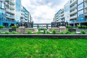 Grimsby (Grimsby Beach) condo for rent - A grassy area in front of apartment buildings with a bridge in the background.