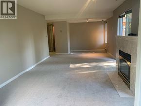 North Vancouver apartment for rent - A spacious living room with a fireplace and a door in the background.