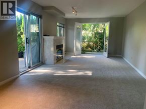 North Vancouver apartment for rent - A spacious living room with a fireplace and sliding glass doors leading to a garden.