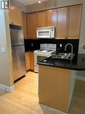 Vaughan (Islington Woods) condo for rent - A kitchen with wooden cabinets and a black counter top.