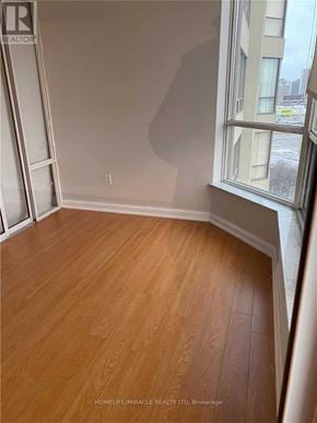 Brampton (Queen Street Corridor) condo for rent - A room with wooden flooring and a window showing a city view.