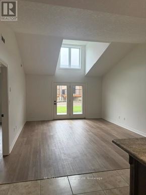Wellington North (Mount Forest) townhouse for rent - A large empty room with a skylight and a door leading to a balcony.