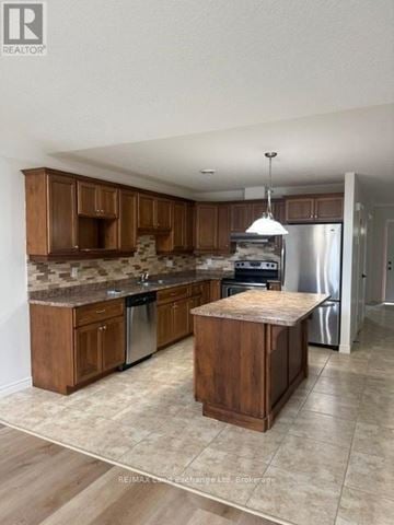 Wellington North (Mount Forest) townhouse for rent - A kitchen with wooden cabinets and a marble backsplash.