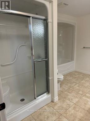 Wellington North (Mount Forest) townhouse for rent - A bathroom with a glass shower door and a toilet.