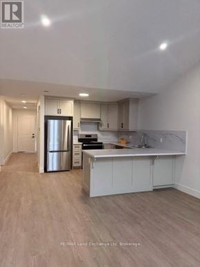 Wellington North (Mount Forest) townhouse for rent - A kitchen with white cabinets and a wooden floor.
