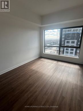 Clarington (Bowmanville) condo for rent - A room with wooden flooring and a large window showing a cityscape.