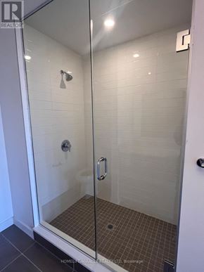 Clarington (Bowmanville) condo for rent - A glass shower stall with a door and a shower head.