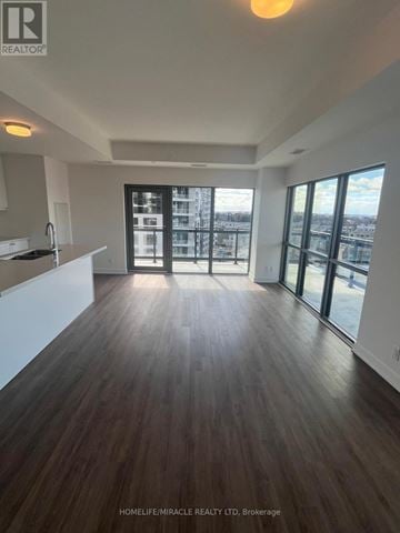 Clarington (Bowmanville) condo for rent - A spacious room with wooden flooring and large windows.