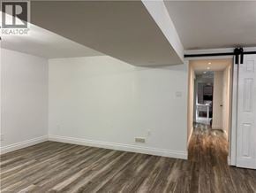 Ancaster apartment for rent - A room with wooden flooring and white walls, leading to another room.