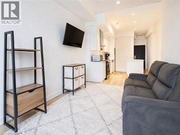 Kitchener condo for rent - A living room with a grey couch and a flat screen TV mounted on the wall.