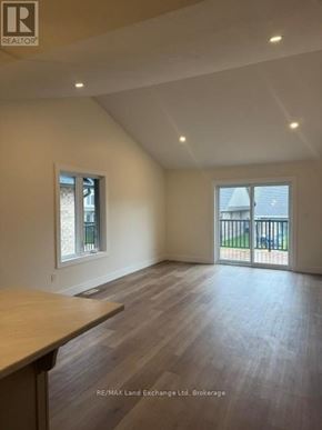 Wellington North (Mount Forest) townhouse for rent - A spacious room with wooden flooring and a sliding glass door leading to a balcony.