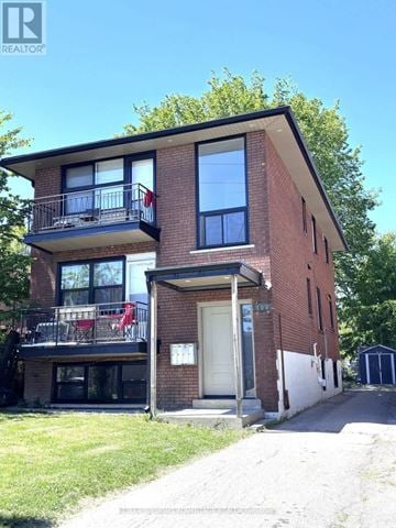 Toronto (Mimico) triplex for rent - A two-story brick house with a balcony on the upper floor.