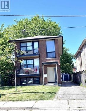 Toronto (Mimico) triplex for rent - A two-story brick building with a balcony on the second floor.