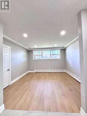 Toronto (Mimico) triplex for rent - A room with wooden flooring and a window with a view of a cityscape.