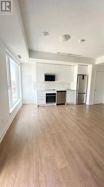 Vaughan (Concord) condo for rent - A spacious kitchen with wooden floors and white walls.