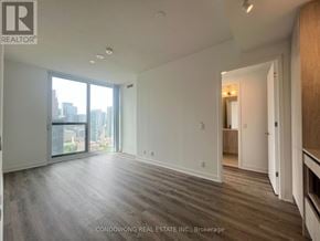 Toronto (Moss Park) condo for rent - A spacious room with wood flooring and a view of the city through the windows.