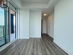 Toronto (Moss Park) condo for rent - A spacious room with wooden flooring and white walls.