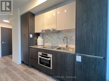 Toronto (Moss Park) condo for rent - A modern kitchen with dark wood cabinets and a marble backsplash.