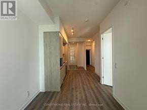Toronto (Moss Park) condo for rent - A spacious room with wood flooring and white walls.