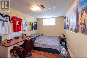 Thorold (Confederation Heights) apartment for rent - A bedroom with a bed, desk, chair, and sports jerseys hanging on the wall.