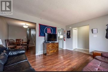Thorold (Confederation Heights) apartment for rent - A living room with a black leather couch and a wooden cabinet.