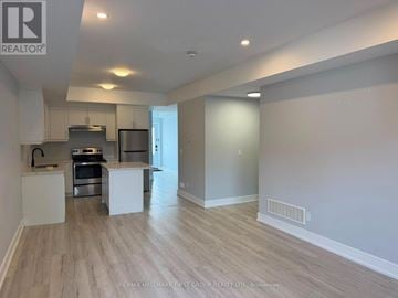 Oshawa (O'neill) triplex for rent - A spacious kitchen with white cabinets and a stainless steel oven.