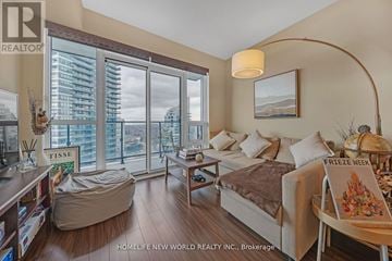 Toronto (Mimico) condo for rent - A living room with a large window and a view of a city skyline.