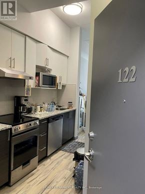 Hamilton (Ainslie Wood) condo for rent - A modern kitchen with stainless steel appliances and a grey door with the number 122 on it.