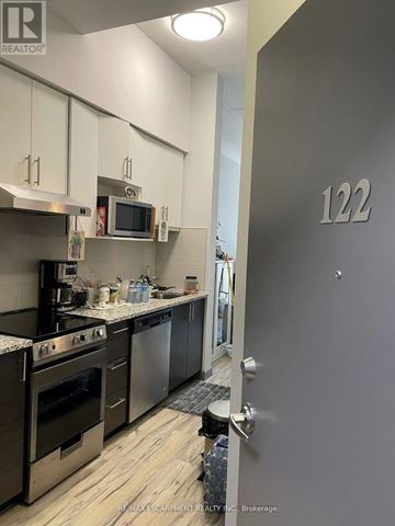 Hamilton (Ainslie Wood) condo for rent - A modern kitchen with stainless steel appliances and a grey door with the number 122 on it.