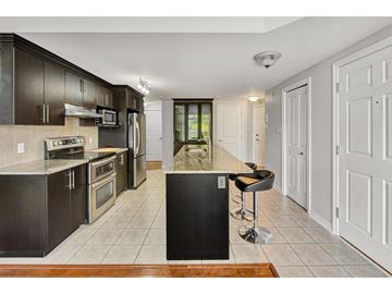 Gatineau (Aylmer) condo for rent - A kitchen with dark brown cabinets and a black island.