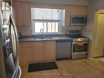 Toronto (Yorkdale-Glen Park) triplex for rent - A kitchen with wooden cabinets and a stainless steel refrigerator.