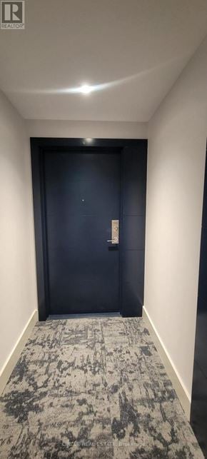 Hamilton (Corktown) condo for rent - A hallway with a carpeted floor and a closed dark blue door.