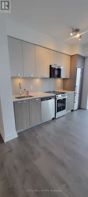 Hamilton (Corktown) condo for rent - A modern kitchen with wooden cabinets and stainless steel appliances.