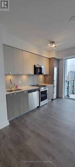 Hamilton (Corktown) condo for rent - A modern kitchen with wooden floors and white walls.