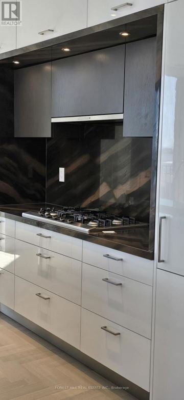 Toronto (Waterfront Communities) condo for rent - A modern kitchen with white cabinets and a dark countertop.