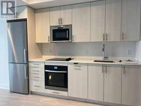 Oshawa (Windfields) condo for rent - A modern kitchen with a stainless steel refrigerator and white cabinets.
