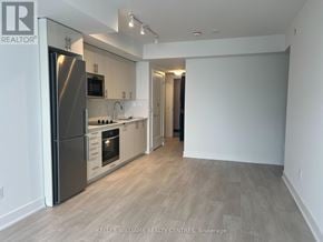 Oshawa (Windfields) condo for rent - A spacious kitchen with a refrigerator, microwave, oven, and sink.