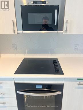 Oshawa (Windfields) condo for rent - A kitchen with a black microwave and a black stove top.