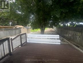 Brampton (Madoc) apartment for rent - A wooden deck with a white railing and a tree in the background.