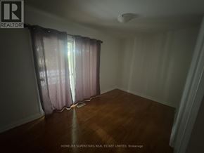 Brampton (Madoc) apartment for rent - A room with a wooden floor and a window with curtains.