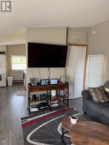 Tillsonburg duplex for rent - A living room with a grey couch, a coffee table, and a television mounted on the wall.